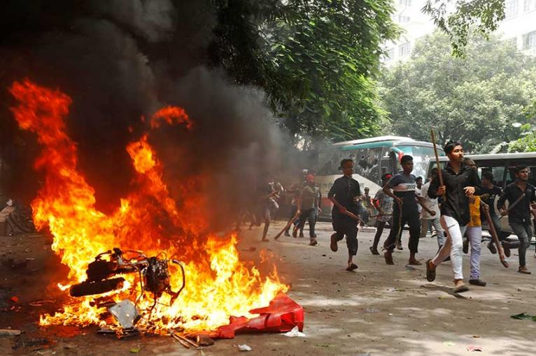 হাসিনা পদত্যাগের আগের দিন ৪ আগস্ট, ২০২৪-এ প্রধানমন্ত্রী শেখ হাসিনা এবং তার সরকারের বিরুদ্ধে সমাবেশের সময় বঙ্গবন্ধু শেখ মুজিব মেডিকেল বিশ্ববিদ্যালয় হাসপাতালে বিক্ষোভকারীদের দ্বারা আগুন দেওয়া একটি গাড়ির পাশ দিয়ে লোকেরা দৌড়াচ্ছেন।